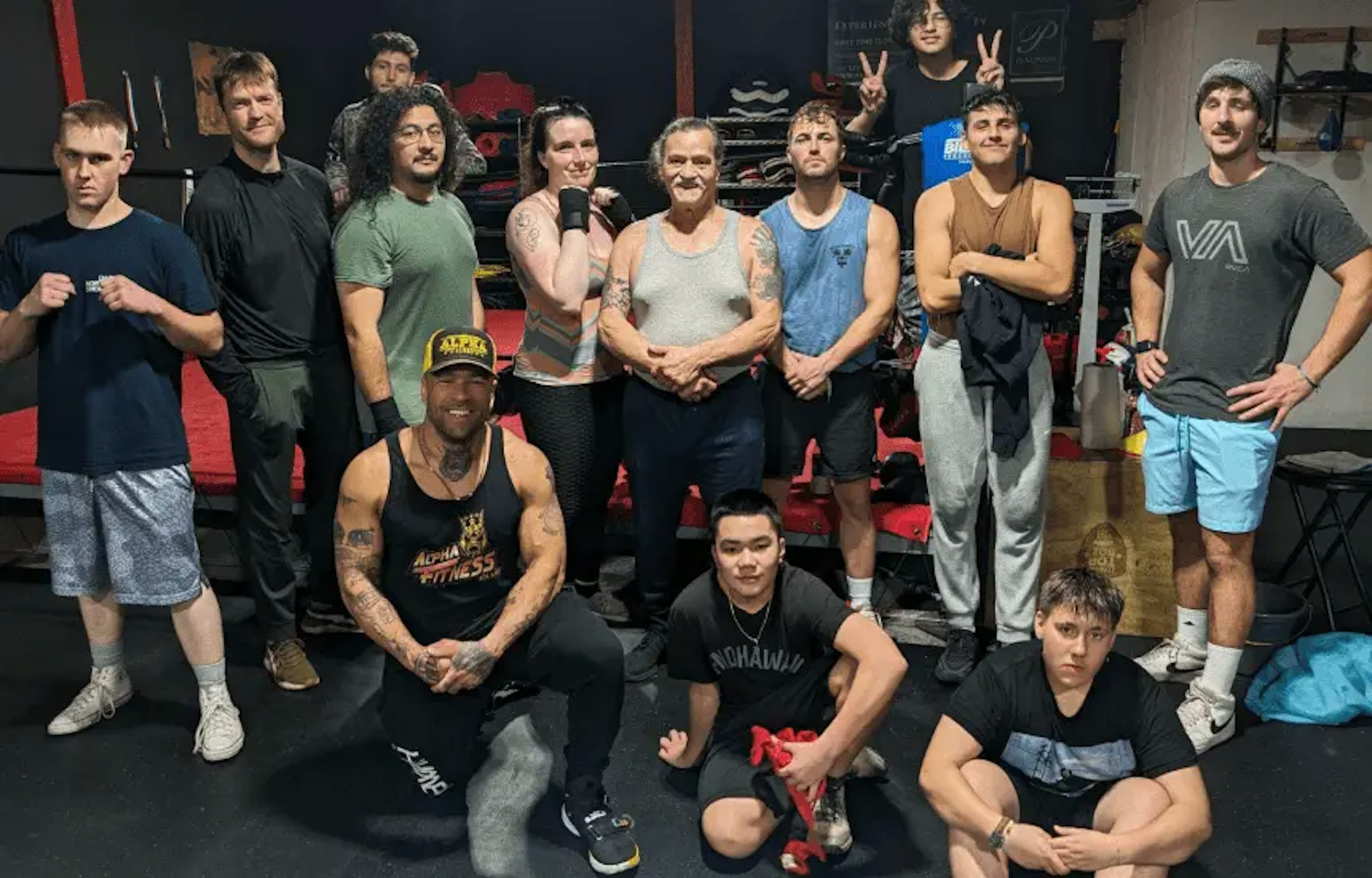 Boxing class members posing for a picture and behind them is a boxing ring.